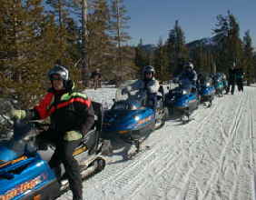 Here geared up and ready to go a group of vacation visitors from Accommodation Tahoe wait to begin their snowmobile adventure.  Snowmobililing is great fun.